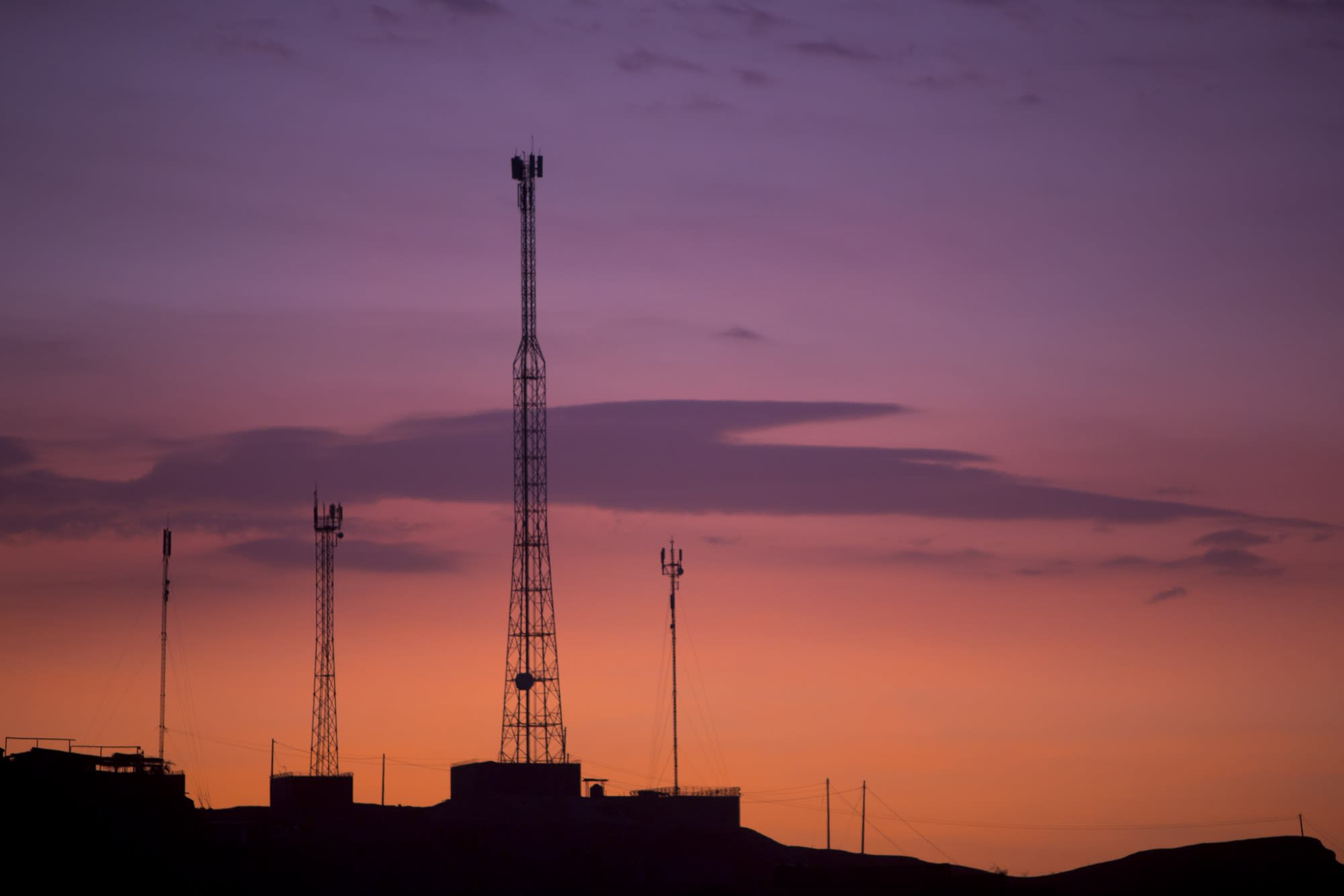 Communication towers on orange purple sky background, Peru