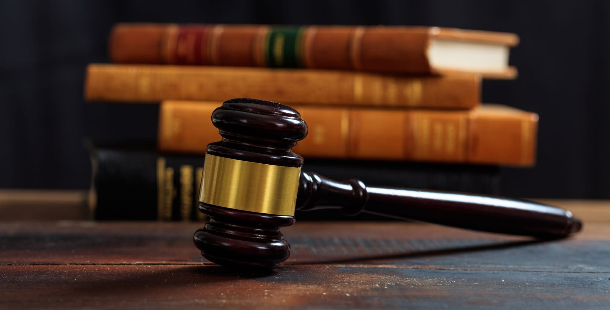 Judge gavel on a wooden desk, law books background